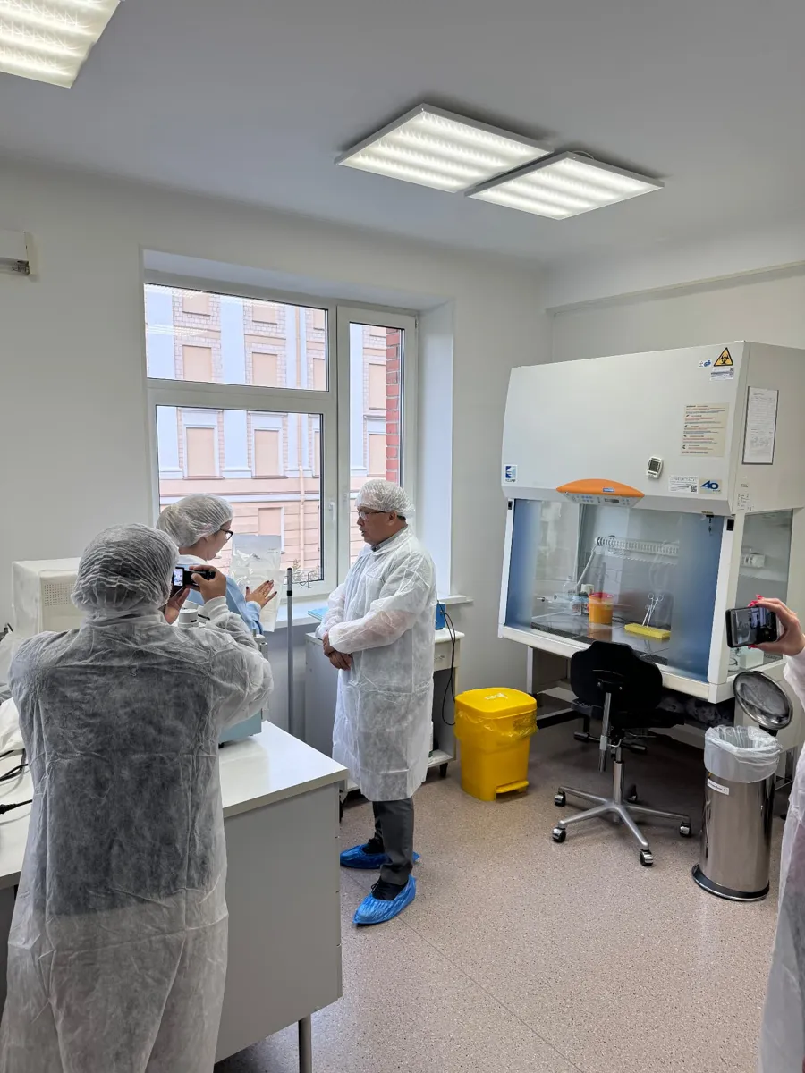 Professionals in sterile attire talk in a cell culture laboratory
