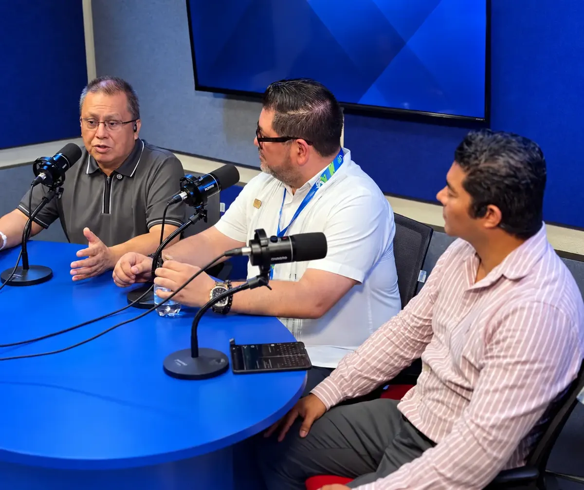 Dr. Gerardo Zumbana speaks with two guests in a radio studio