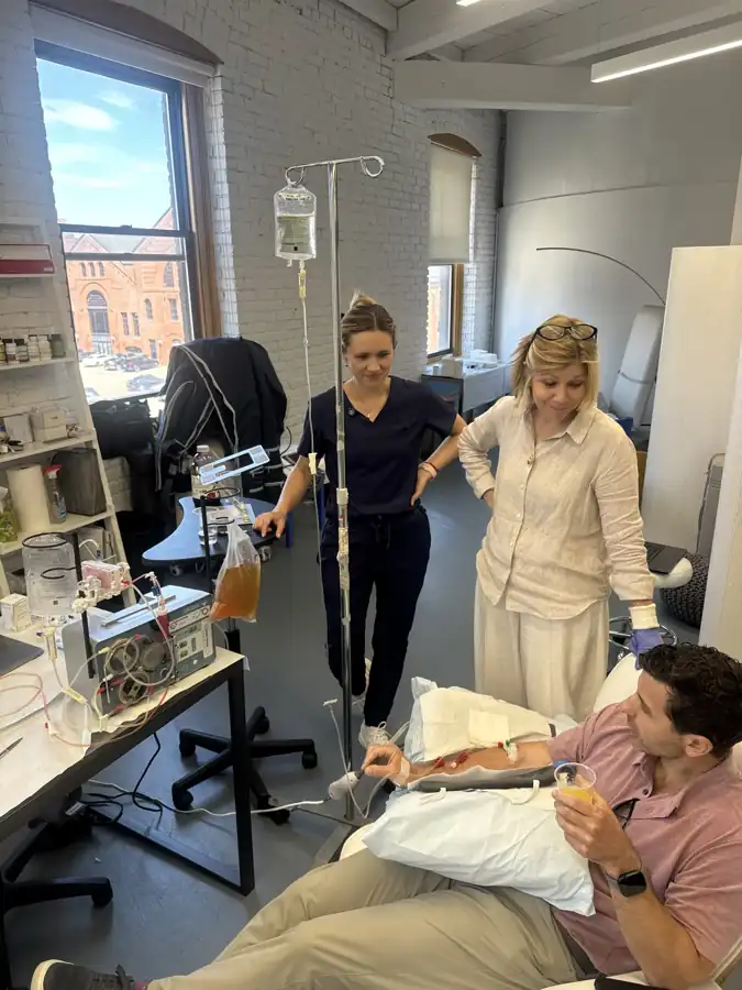 Reclining patient, two professionals and an apheresis circuit in a Boston room